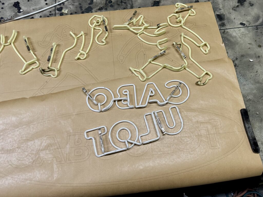 Fabrication artisanale en atelier de l'enseigne néon verre pour le Caboulot à Paris 18ème, tubes soufflés sur gabarit de traçage.