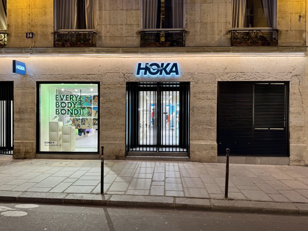 vue de face de la devanture de la boutique HOKA le Marais équipée d'une enseigne de façade et d'une enseigne drapeau
